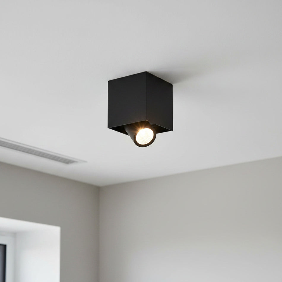 adjustable black surface downlight mounted in a white ceiling 