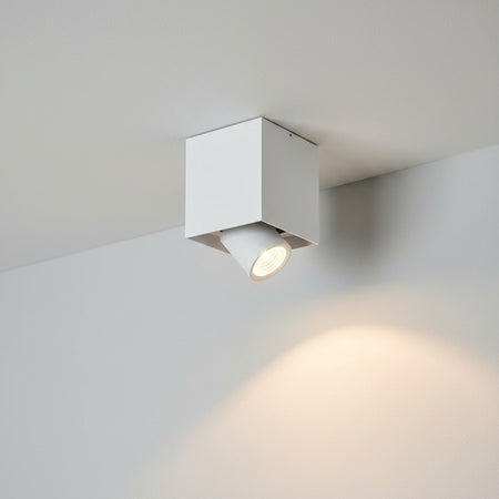 white surface mounted ceiling downlight mounted on a white ceiling next to a wall 