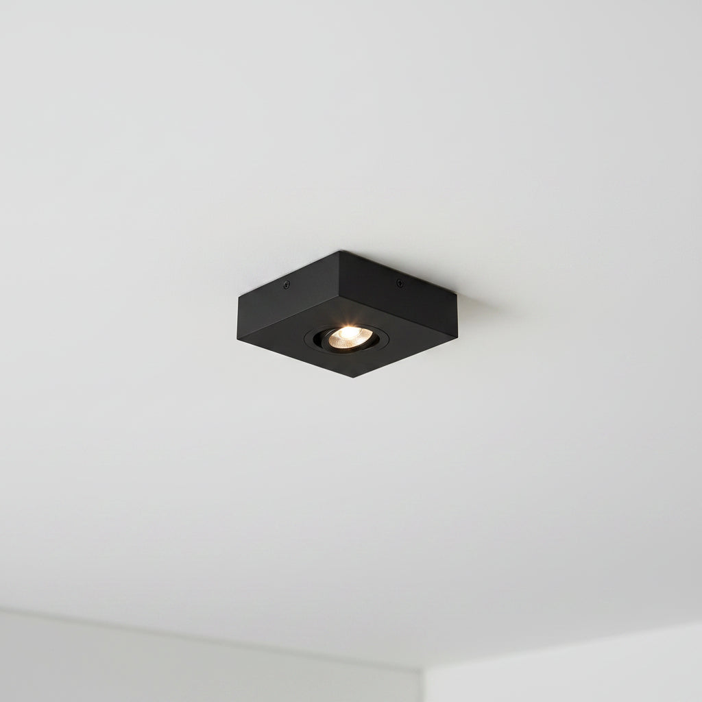 black slimline surface ceiling downlight mounted on a white ceiling 