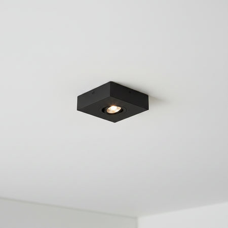 black slimline surface ceiling downlight mounted on a white ceiling 