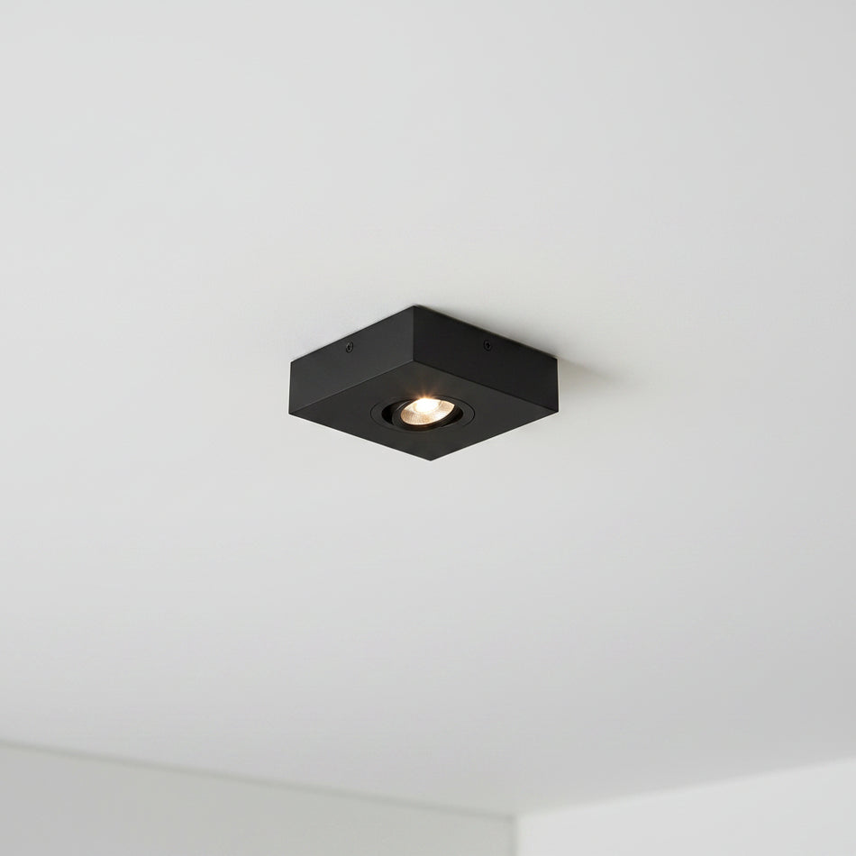 black slimline surface ceiling downlight mounted on a white ceiling 