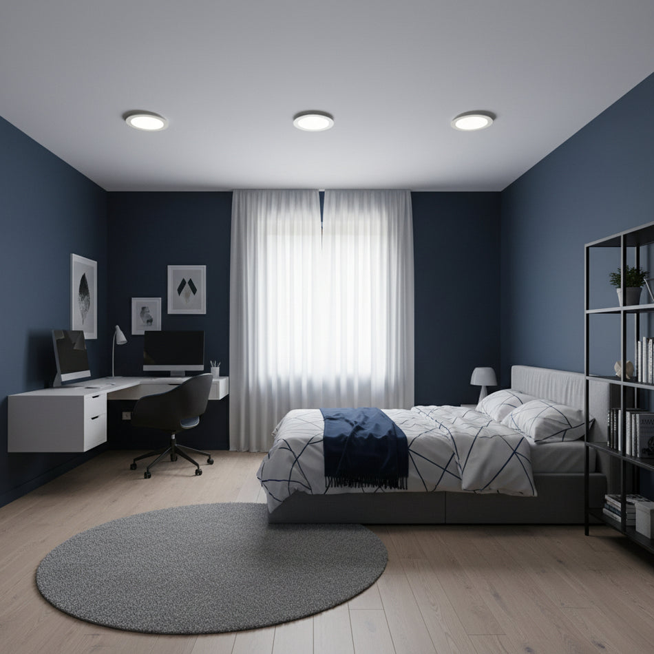 Slimline ceiling downlighter in a bedroom with a bed desk and chair and dark blue walls