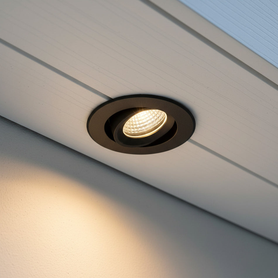black adjustable soffit light mounted in the white soffit of a house