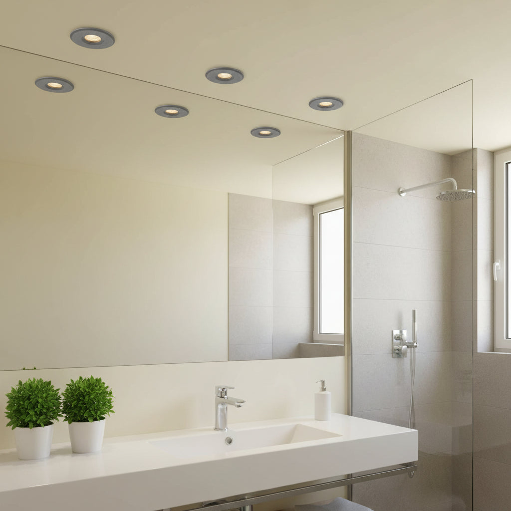 Mini ceiling spotlight above a bathroom sink with plants and a shower to the right of the sink
