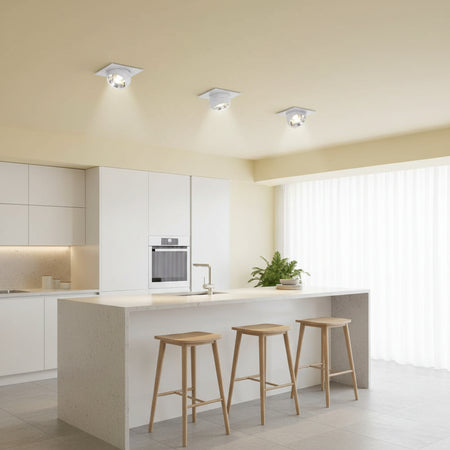 Eyeball downlights above a kitchen breakfast bar on a pale yellow ceiling in a modern house