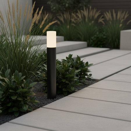 black bollard light installed in a modern home next to a pathway