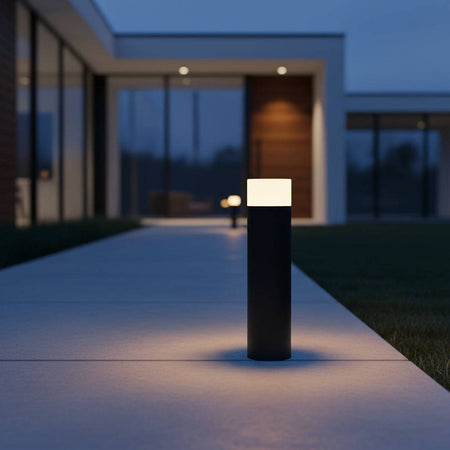 black external bollard light on pathway outside of a modern home