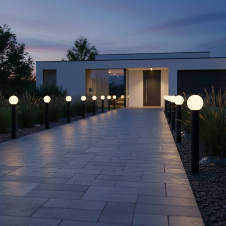 Black outdoor bollard garden light illuminating pathway to front door of a modern house