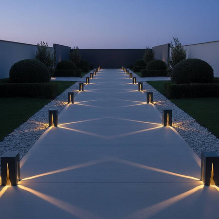 Black square path bollard light on a wide pathway in a modern setting