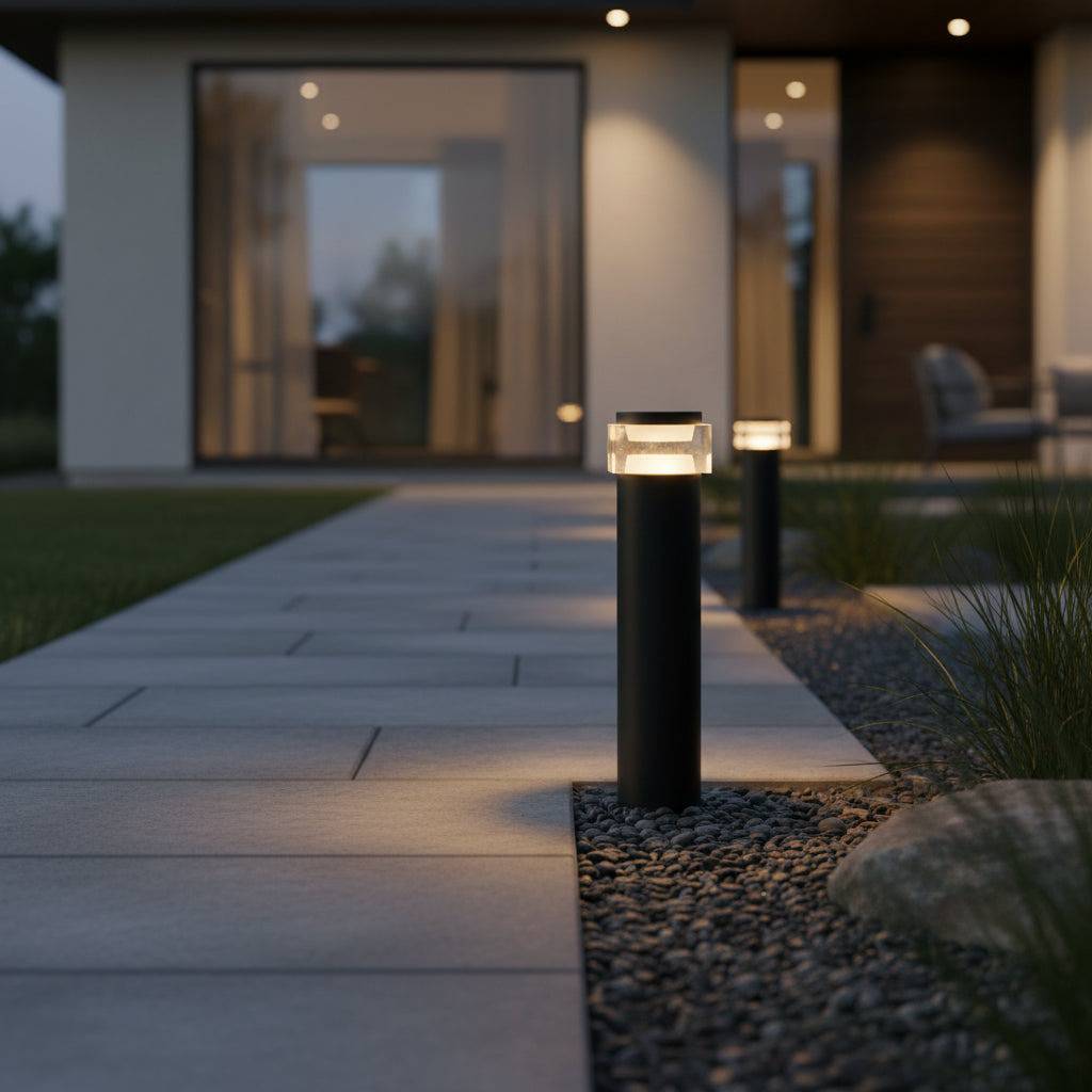 Black square bollard light on grey paved pathway leading to modern house