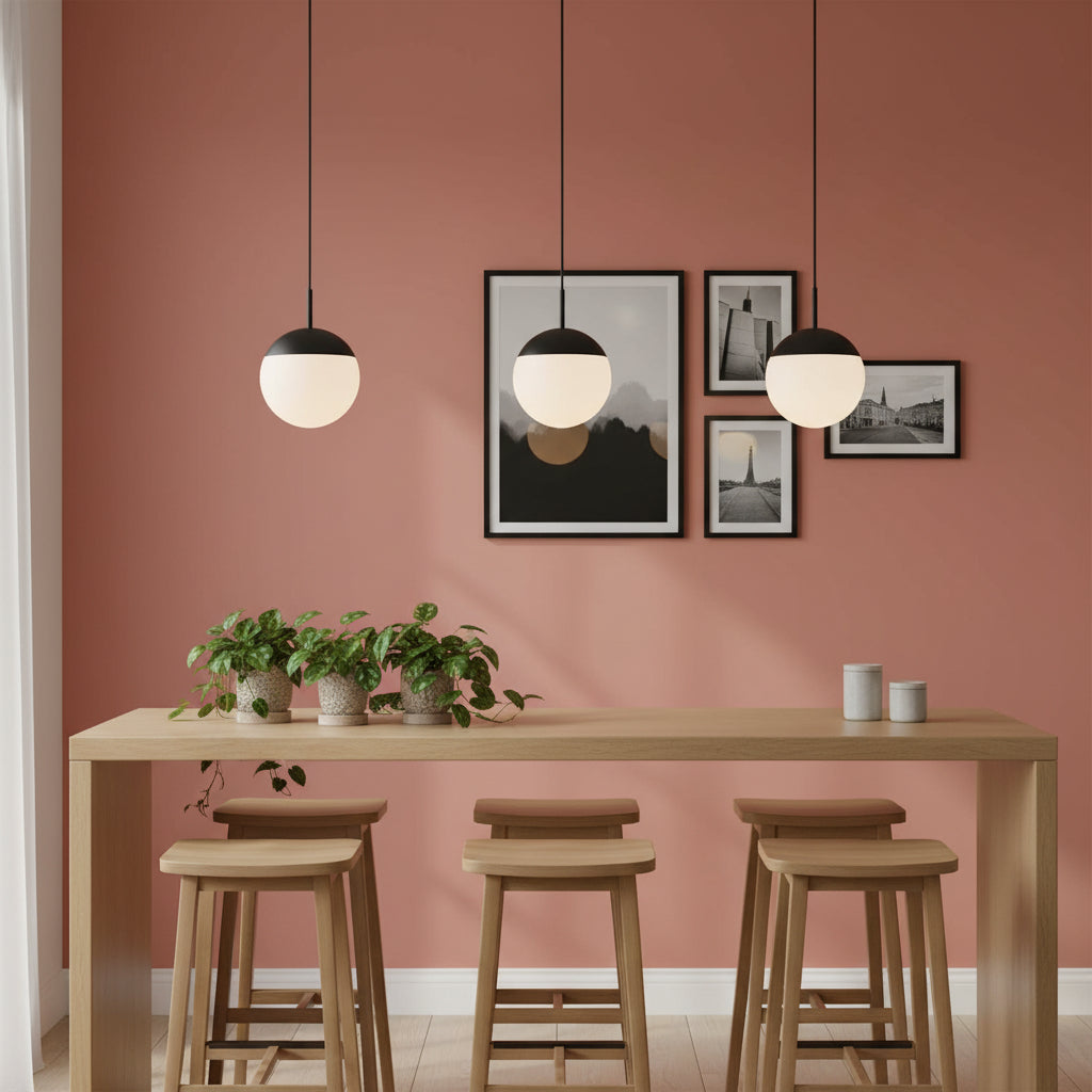 Globe pendant light above a breakfast bar with pictures and plants on a pale red background