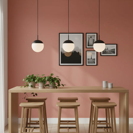 Globe pendant light above a breakfast bar with pictures and plants on a pale red background