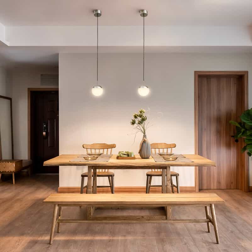White and chrome globe hanging light in a breakfast room over a pine table with chairs and benches