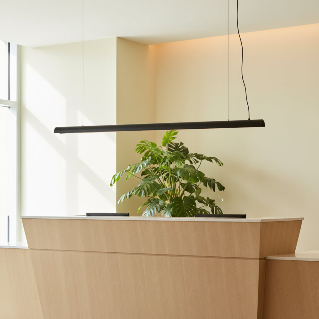 Black linear pendant light n a pale yellow background above a hotel reception desk
