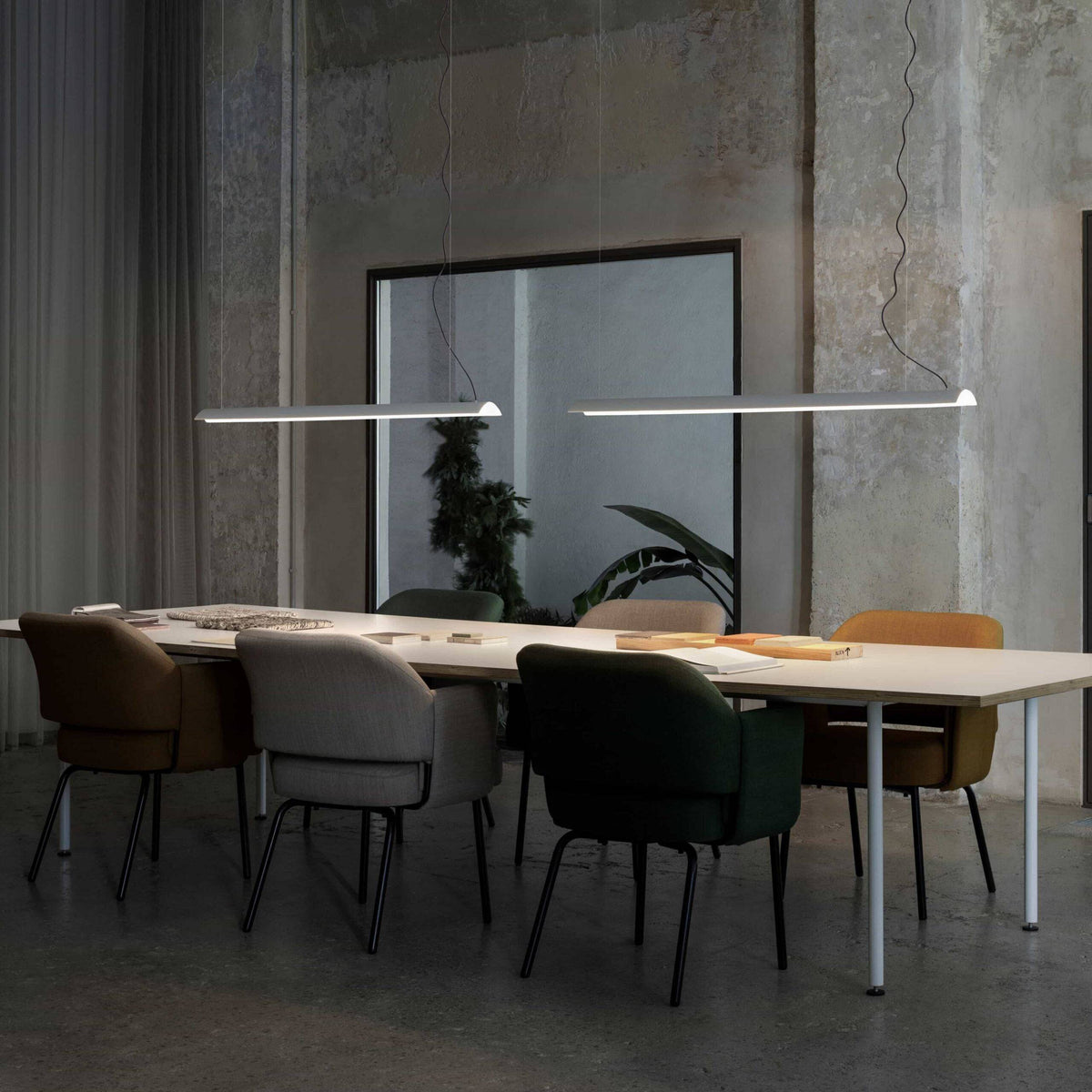 White modern linear pendant light on a grey background with table and chairs
