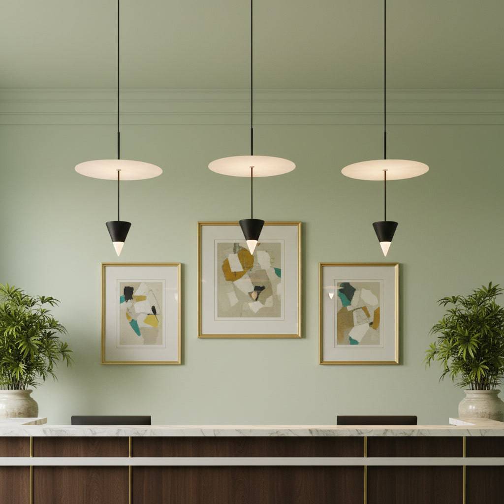 Suspended ceiling light above a hotel reception desk on a pale green back ground with plants and pictures