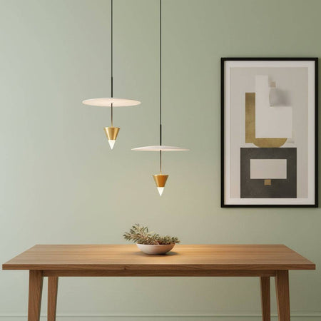 Modern gold pendant light on a pale green background above a table with a picture on the wall