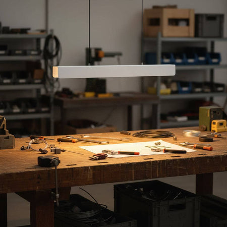 White modern hanging light fixture  above a factory work bench 