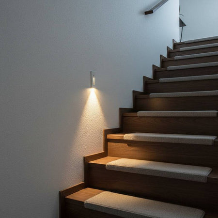 white motion sensor step light installed on a white wall next to a stairway