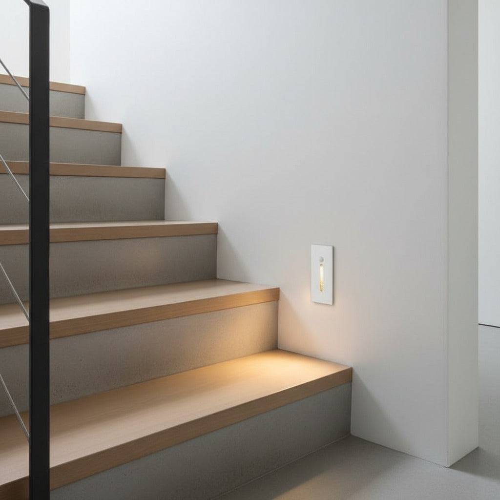 white motion sensor step light installed at the bottom of a staircase on the wall 