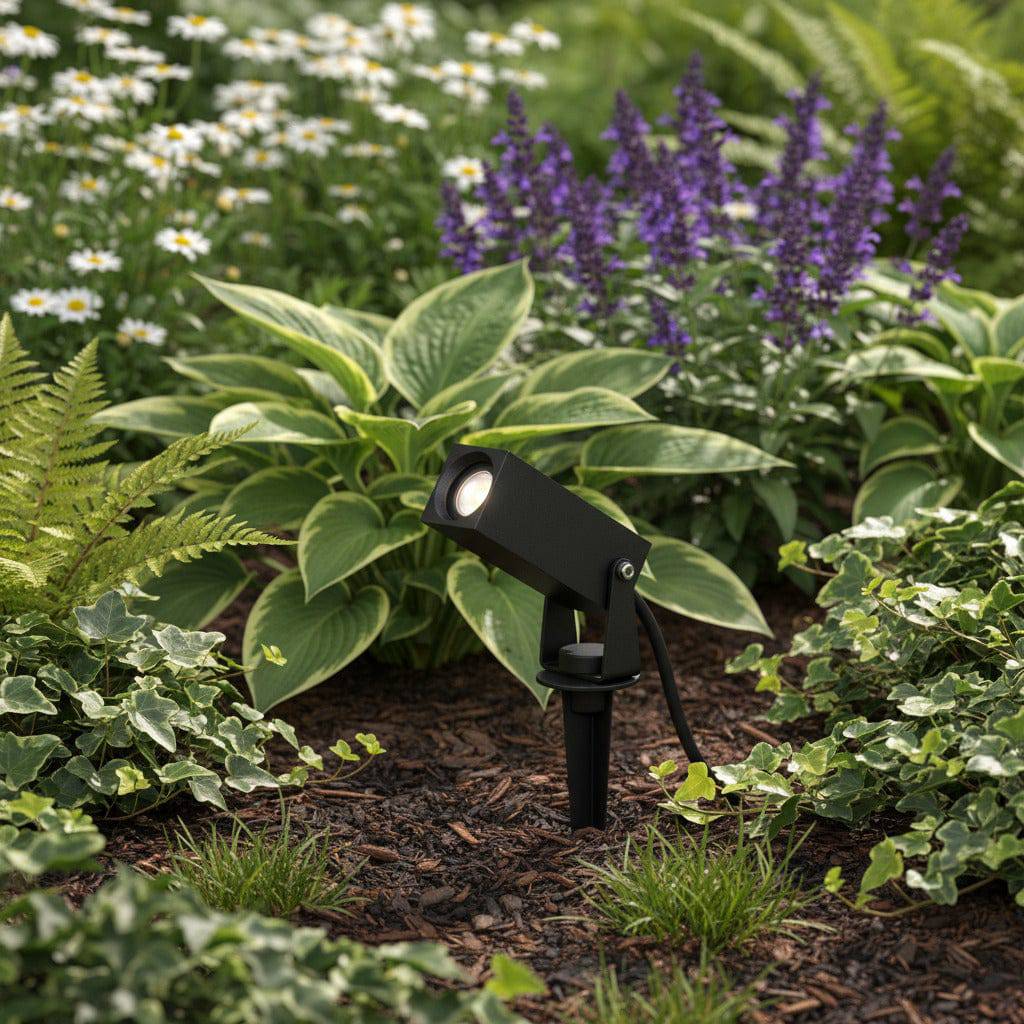black spike light fixture mounted in a planted garden border