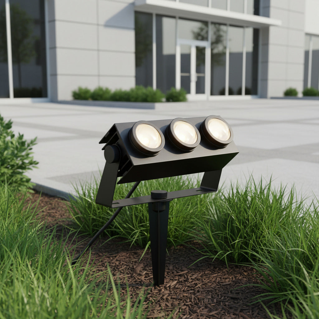 black mains powered spike light installed outside of a commercial building amongst the plants 