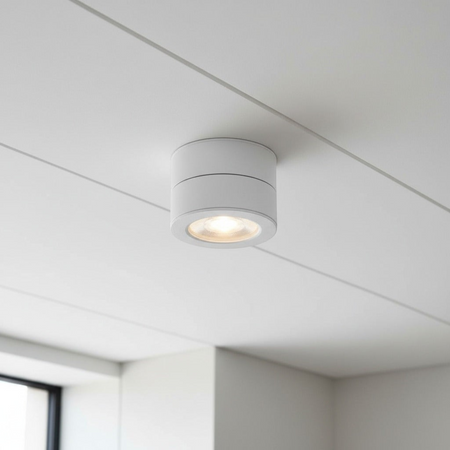 white surface mount adjustable spotlight installed on a white ceiling in a modern house