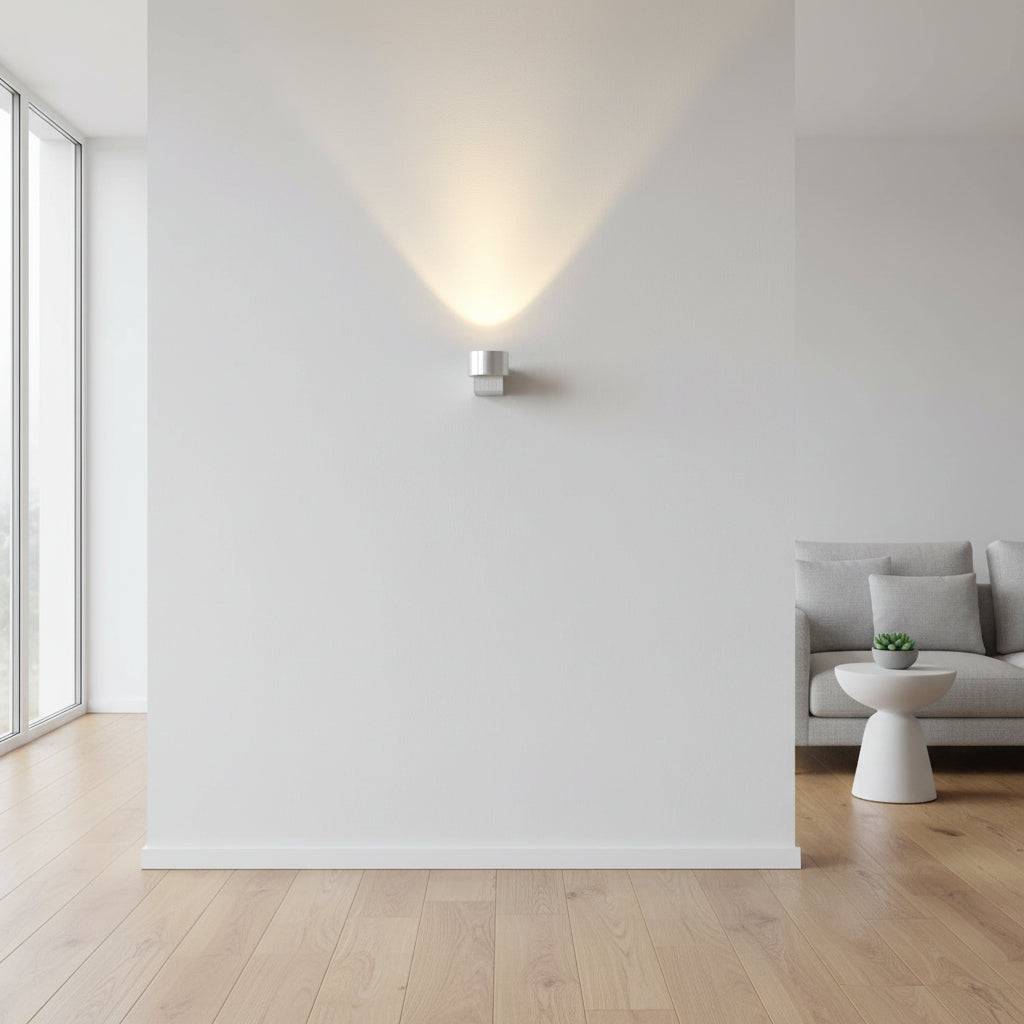 Round silver indoor wall uplight on  a white wall in a lounge