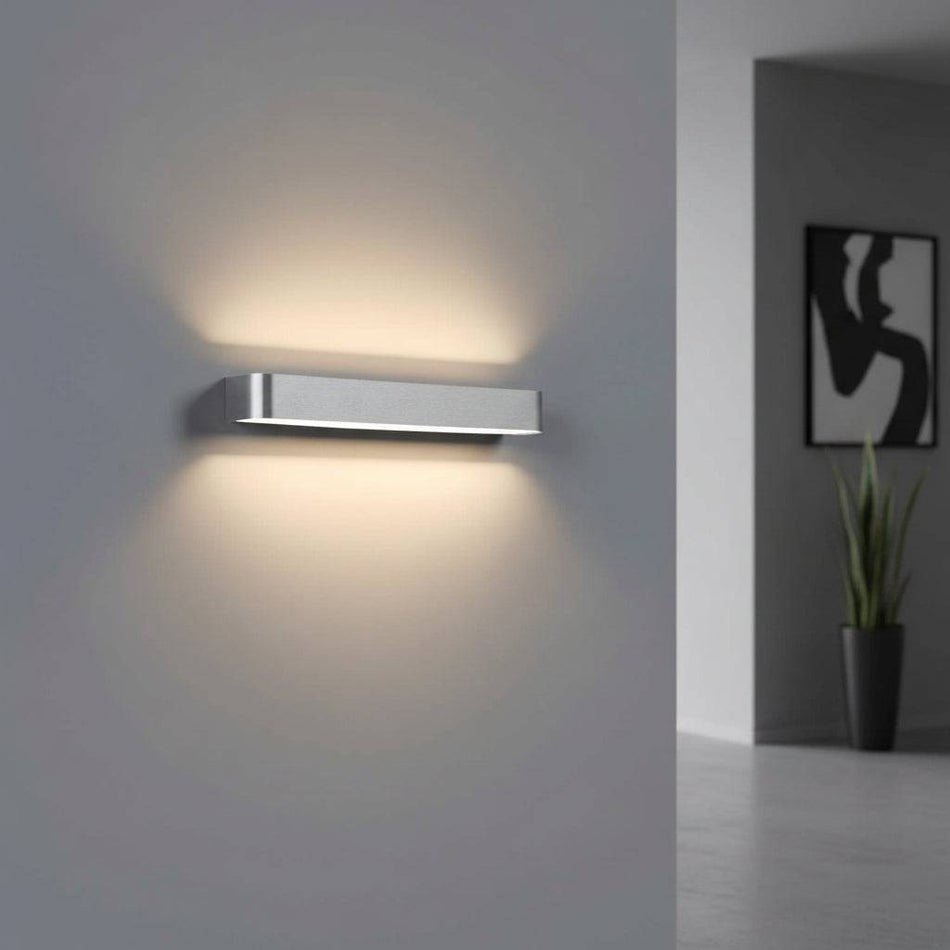 Silver up and down dimmable internal wall light on a grey background in a modern hallway