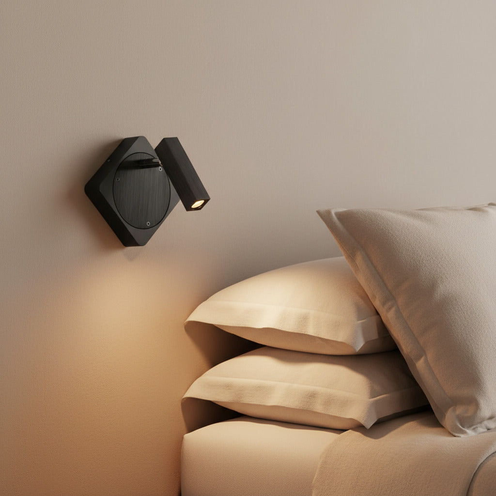 black LED wall reading light mounted on the wall next to a bed