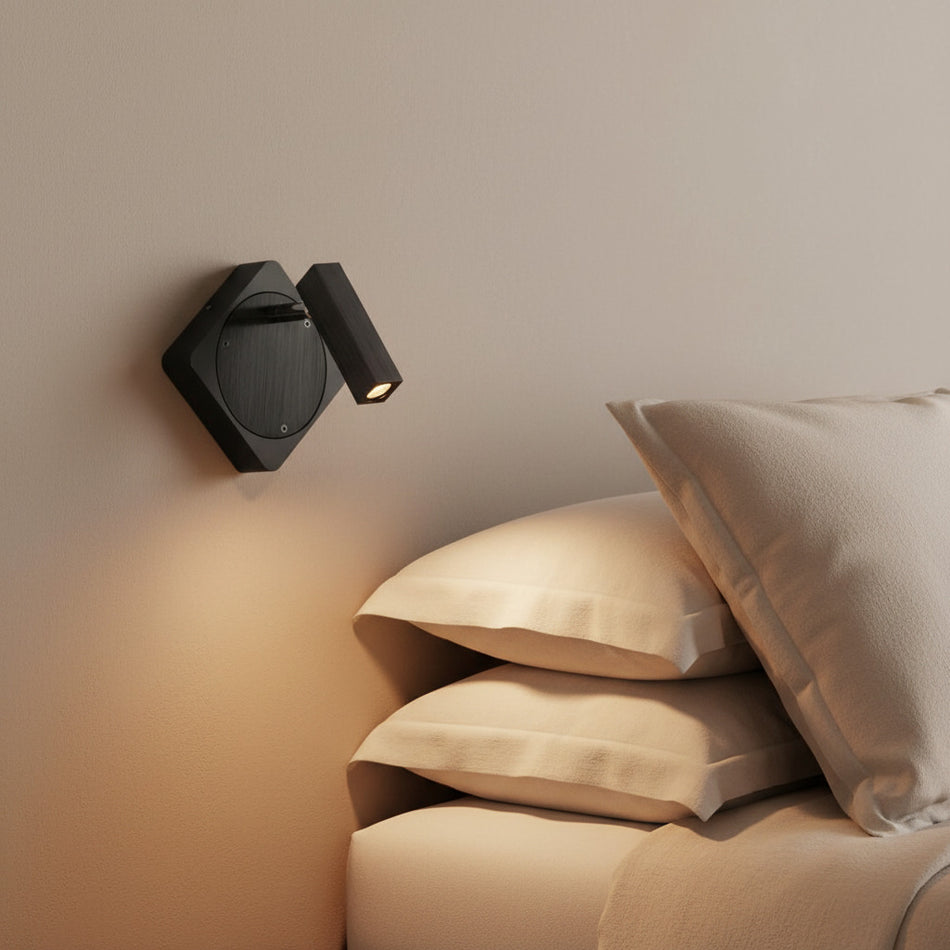 black LED wall reading light mounted on the wall next to a bed