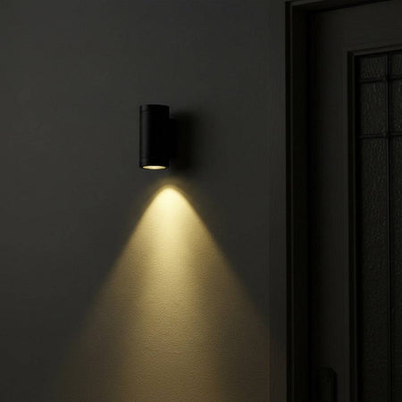 black outdoor LED wall downlight mounted on a textured wall next to a house entrance door