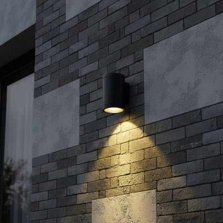 black outdoor wall downlight shining light down an external wall and mounted on a brick wall 