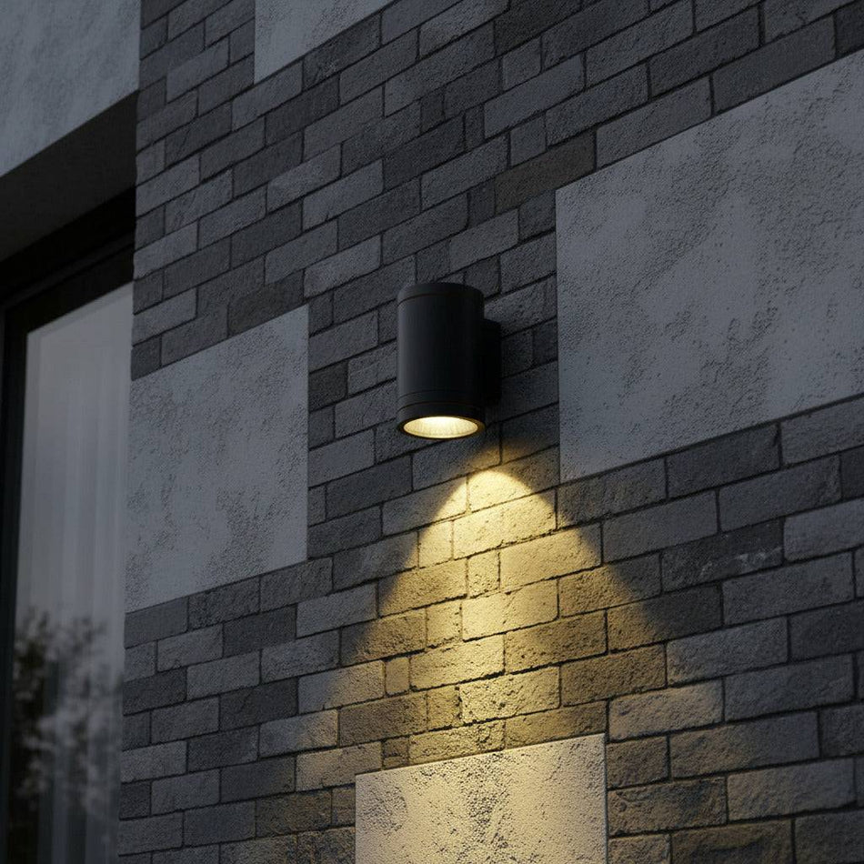 black outdoor wall downlight shining light down an external wall and mounted on a brick wall 