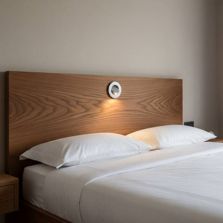 silver recessed wall or headboard reading light mounted in a wooden headboard above a bed