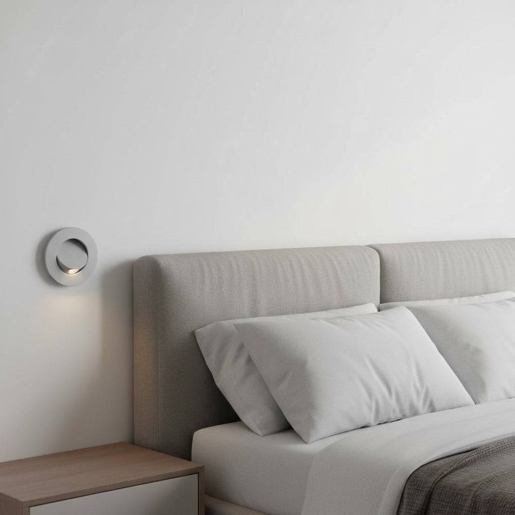 white recessed bedside reading light mounted on the wall next to a bed in a modern clean bedroom