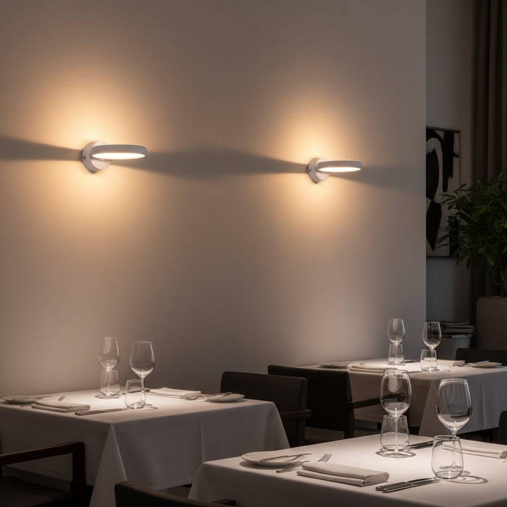 White indoor LED sconce light above tables in a restaurant on a pale grey wall