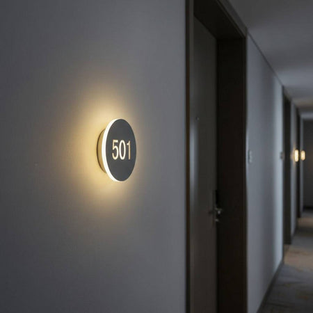 illuminated hotel room door number mounted next to a door in a corridor 