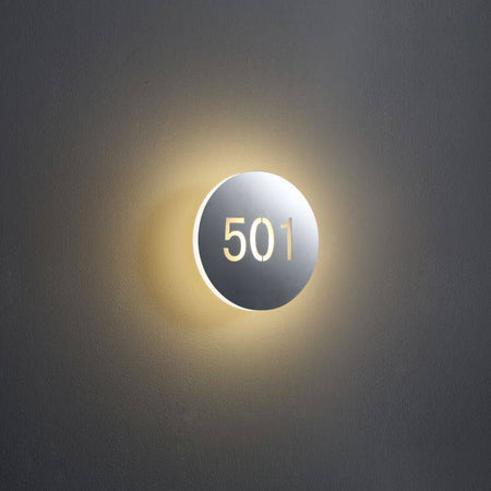 illuminated hotel room door number mounted on a white wall 