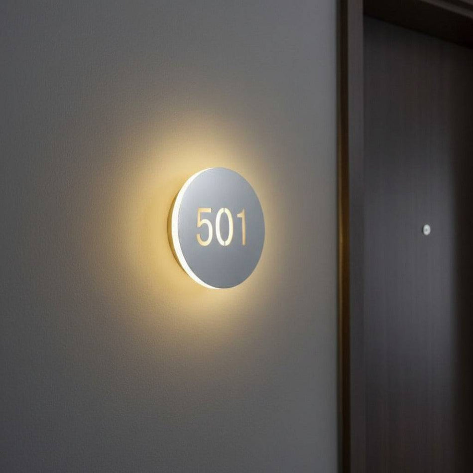 illuminated hotel room number mounted on the wall next to a hotel room door