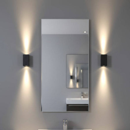 modern black bathroom sconce mounted either side of a mirror in a bathroom