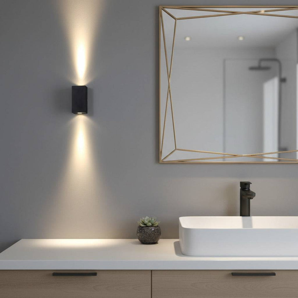 modern black bathroom sconce mounted next to a mirror in a modern bathroom