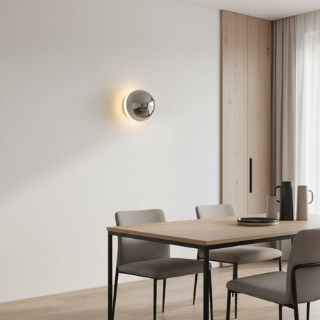 Chrome indoor wall Light on a grey wall above a table and chairs in a modern home
