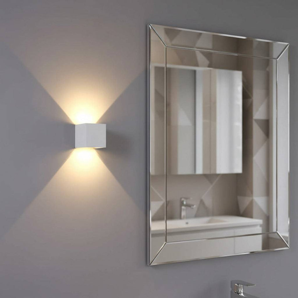white modern bathroom wall light mounted on the wall next to a bathroom mirror 