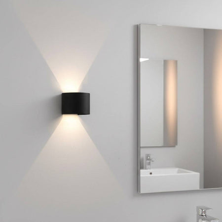 black bathroom wall sconce mounted on the wall in a modern bathroom next to the mirror 