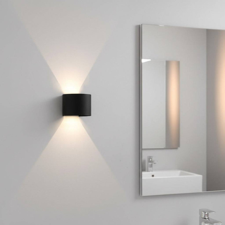 black bathroom wall sconce mounted on the wall in a modern bathroom next to the mirror 