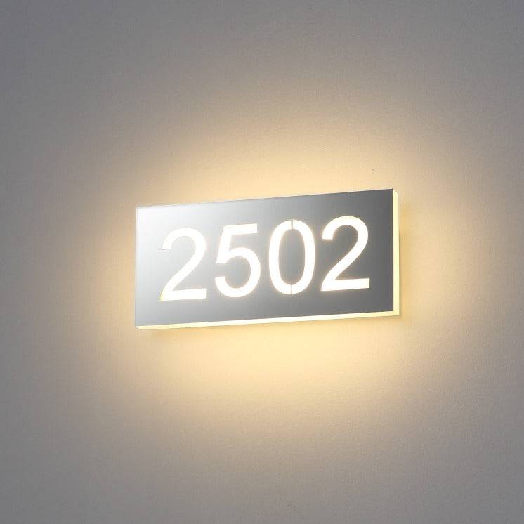 Backlit hotel room number sign installed on a white wall 