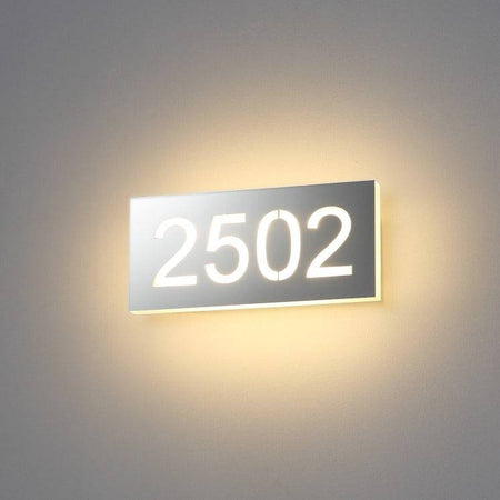 Backlit hotel room number sign installed on a white wall 