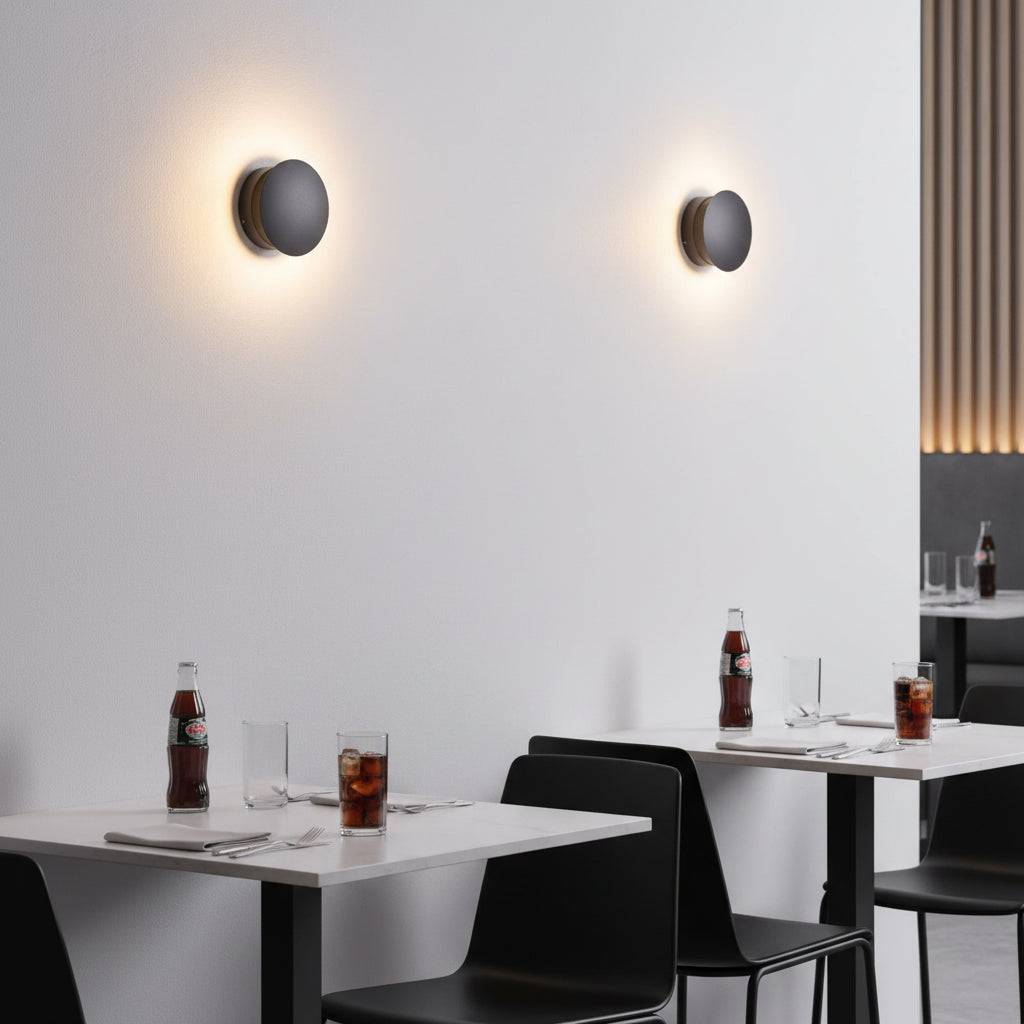 Black inside wall light fixture on a white wall in a restaurant above tables and chairs.