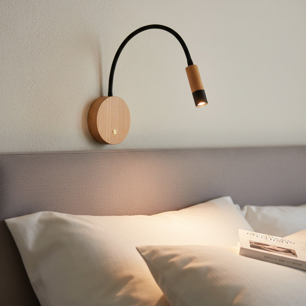 black flexible wooden reading lamp mounted on the wall over a bed 